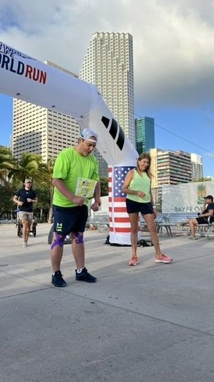 A man and a woman are standing under a banner that says world run