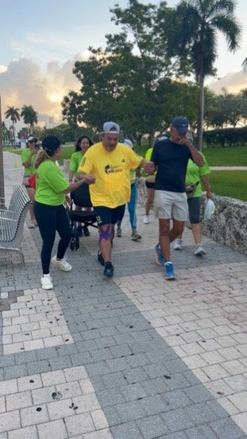 A group of people are walking down a sidewalk and one of them has a yellow shirt on
