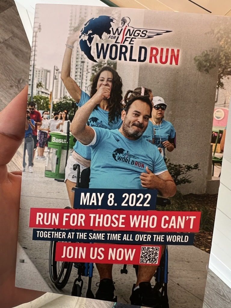 A person is holding a flyer for the wings of the world run
