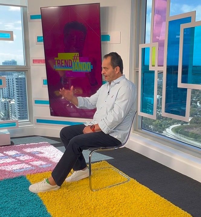 A man is sitting in a chair in front of a screen that says trendy