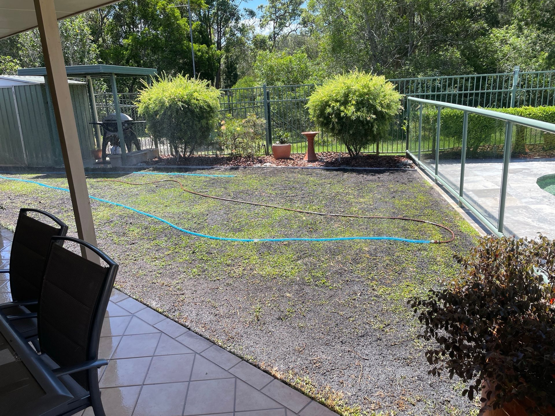 A patio with chairs and a hose in the backyard — Greener Gardens Gardening Service In Thrumster, NSW