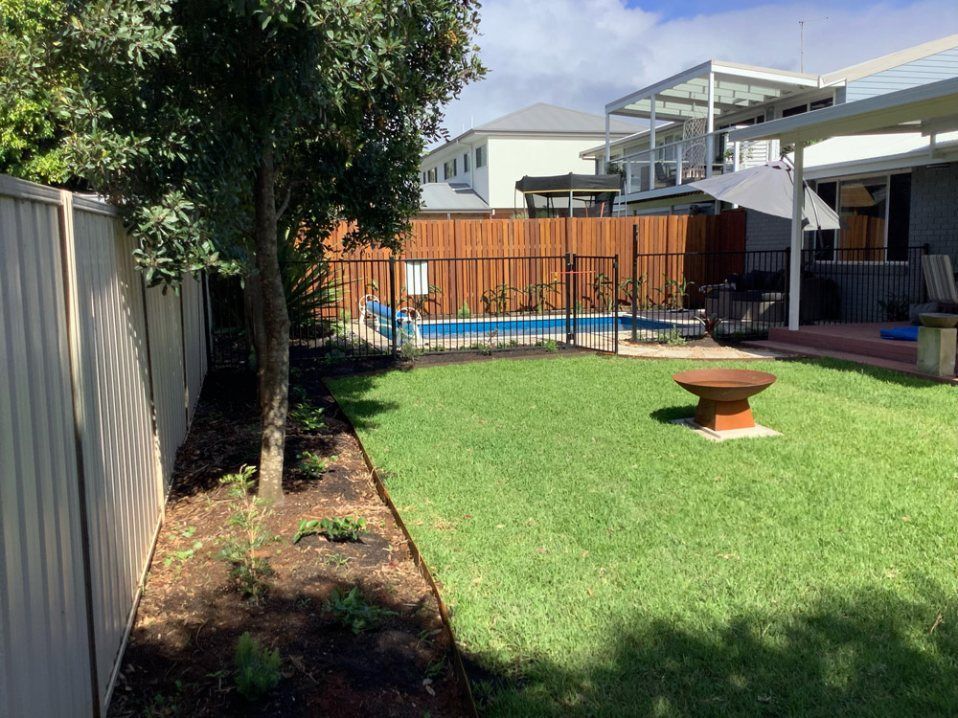 A Fenced in Backyard With a Swimming Pool and a Fire Pit — Greener Gardens Gardening Service In Thrumster, NSW