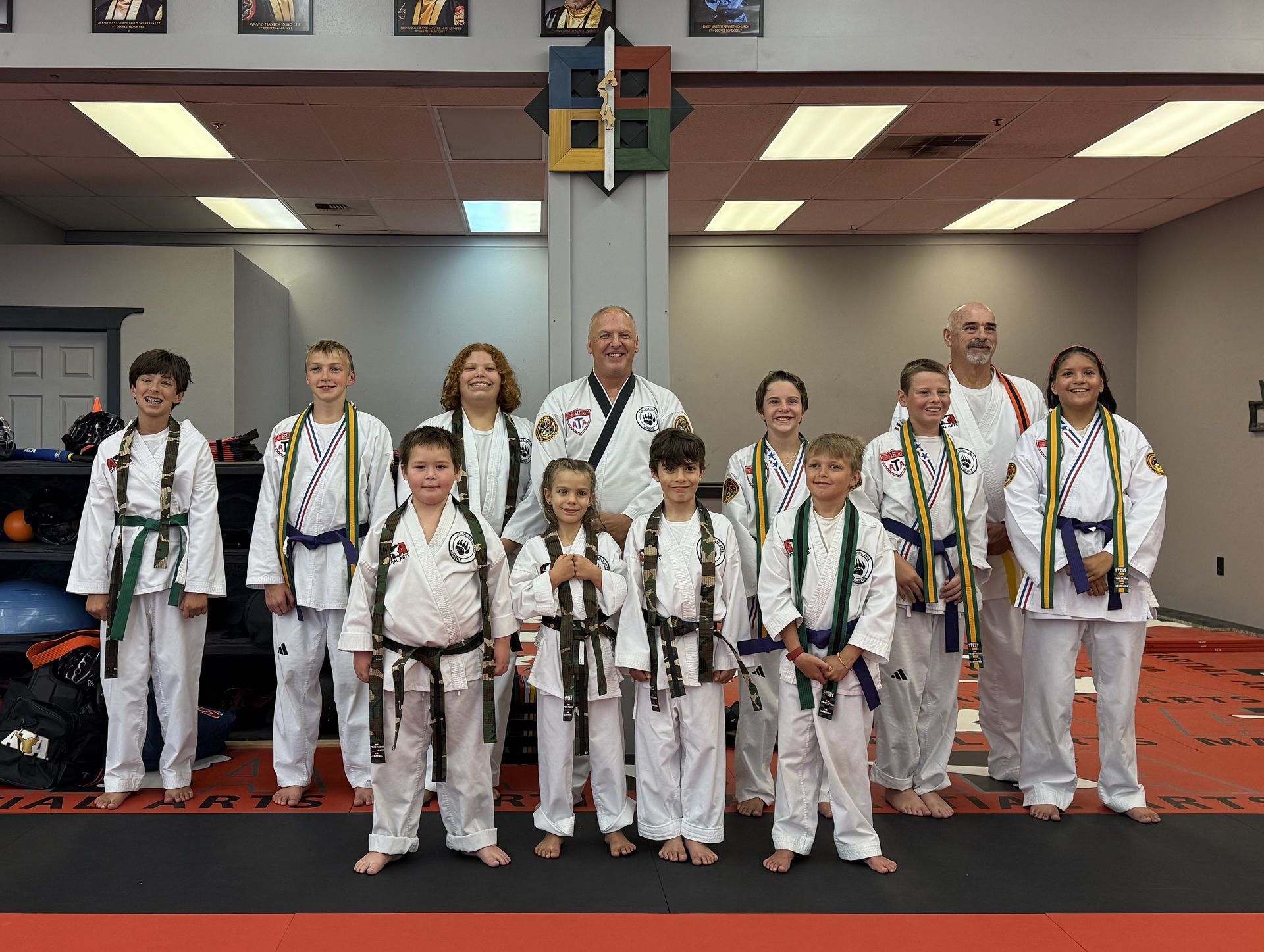 Group of martial arts students in uniforms, posing for a photo in a dojo.