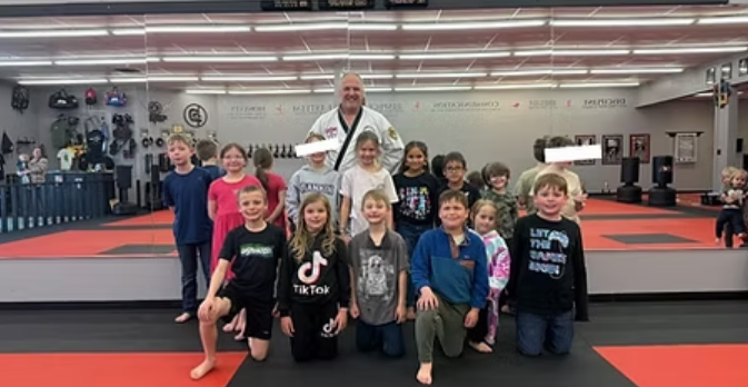 A group of children and an instructor in a martial arts studio.