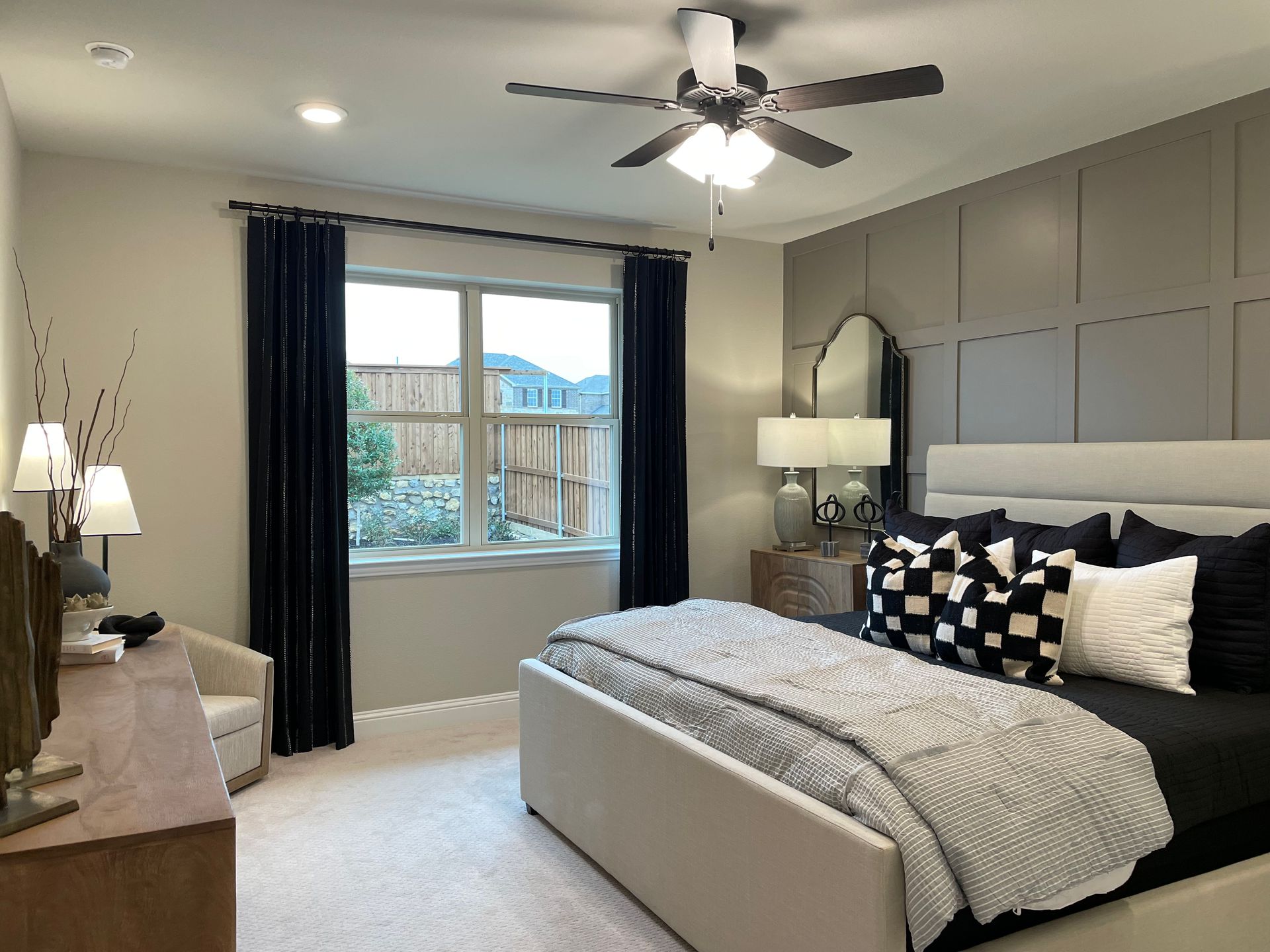 Bedroom with bed, dark blue curtains, gray accent wall, neutral carpet.