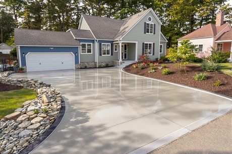Gray house with two-car garage and wide concrete driveway in a landscaped suburban yard