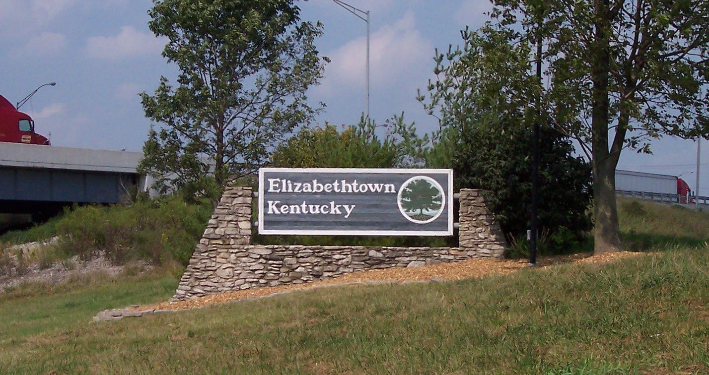 Elizabethtown, Kentucky roadside sign on a stone base beside trees and grass