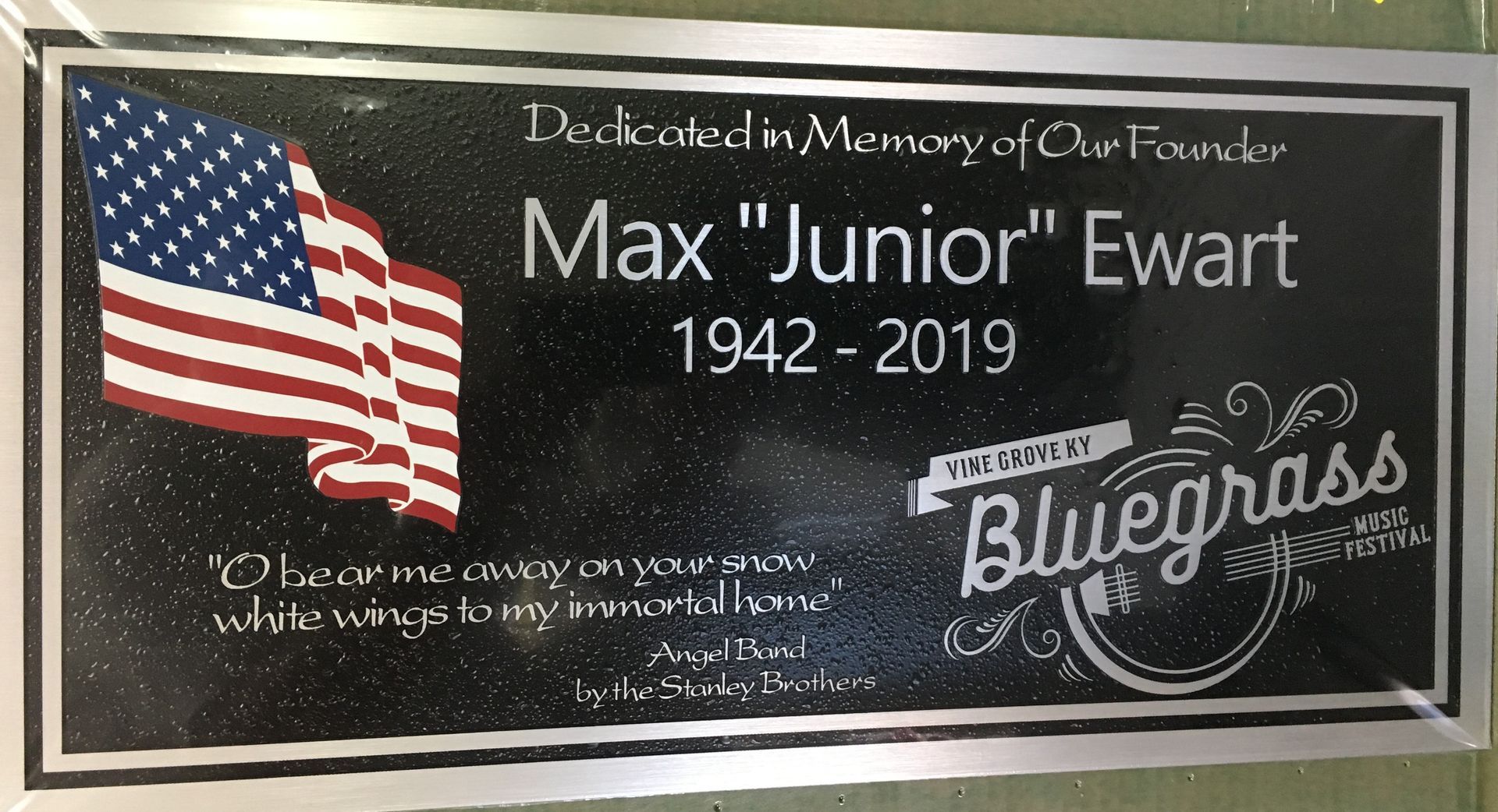 Memorial plaque with American flag, honoring Max “Junior” Ewart, 1942–2019, and Bluegrass Music Hall of Fame