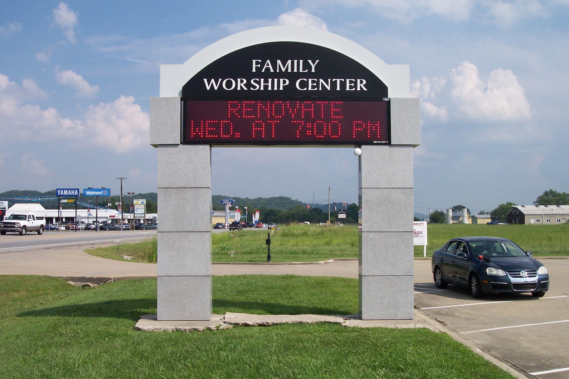 Family Worship Center sign with red digital message beside a parking lot on a cloudy day
