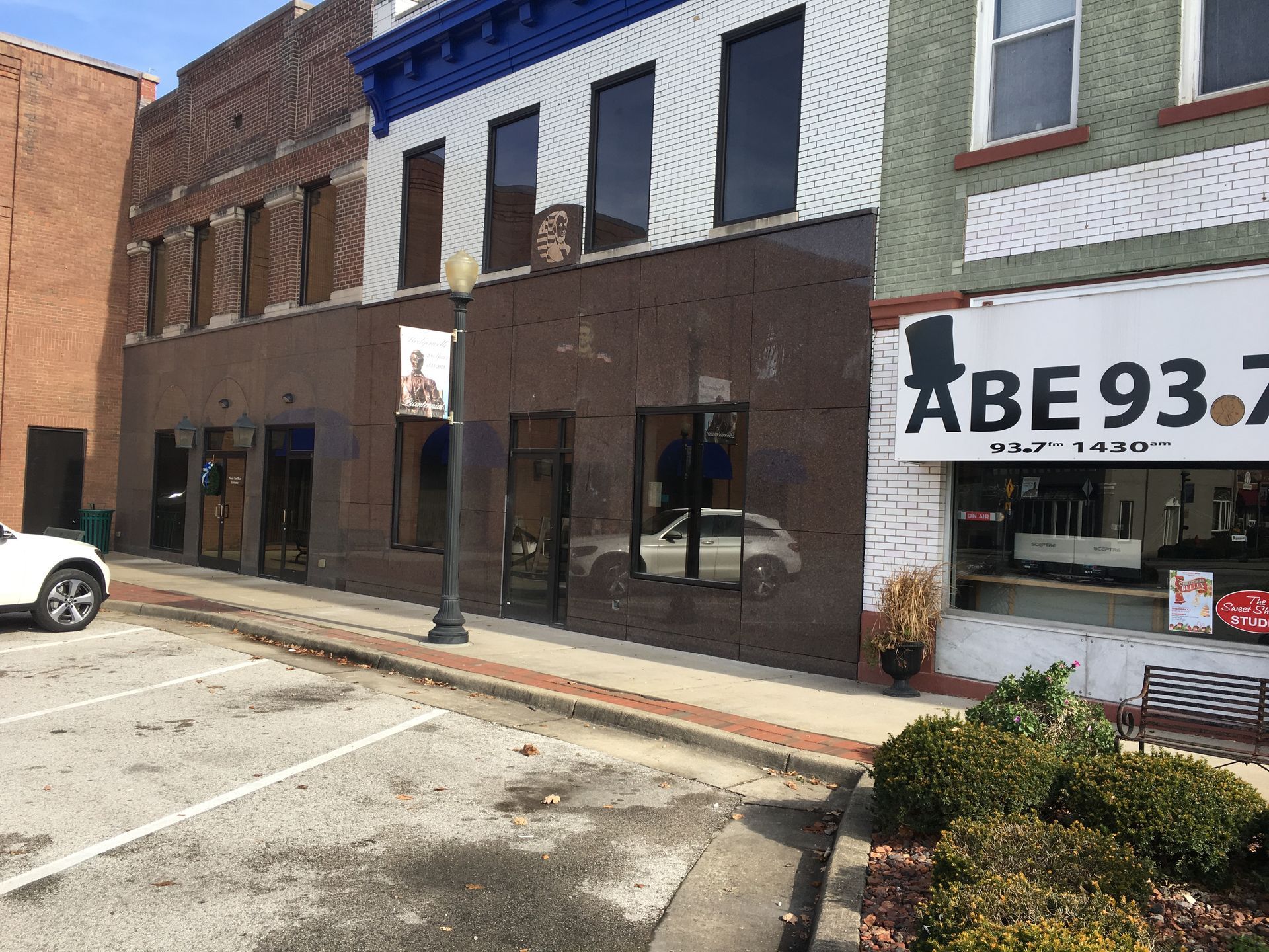 Downtown storefronts on a brick street, including an ABE 93.7 sign on the right.