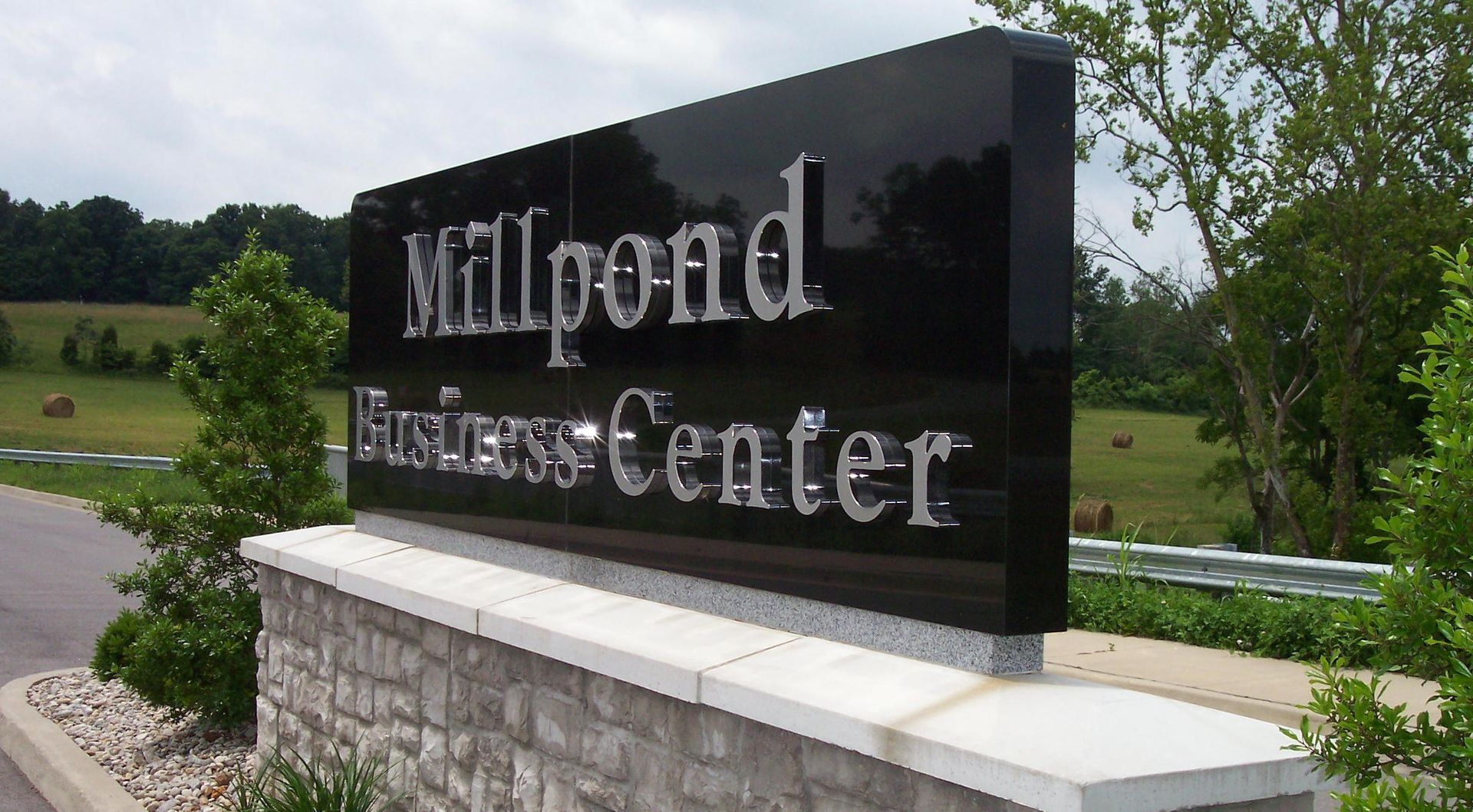 Millpond Inn & Conference Center sign on a stone base by a landscaped road