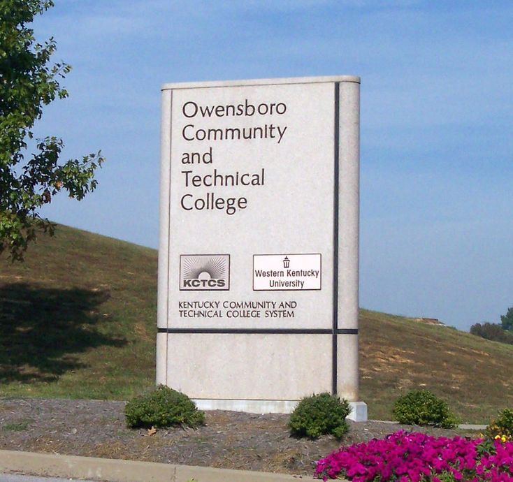 Owensboro Community and Technical College sign beside a grassy roadside under a blue sky