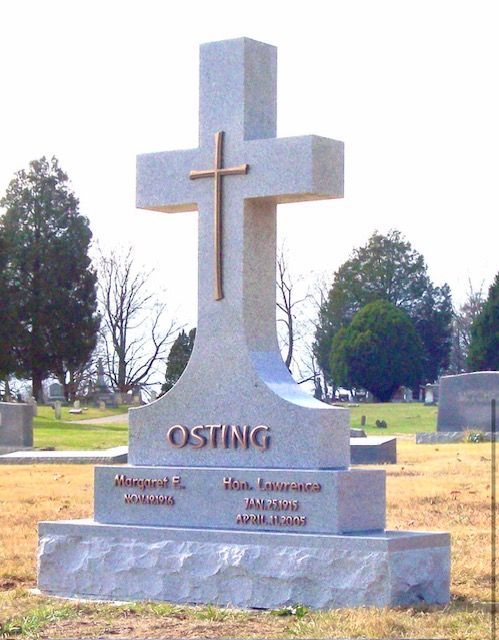 Stone memorial cross gravestone with “OSTING” engraved, standing in a cemetery
