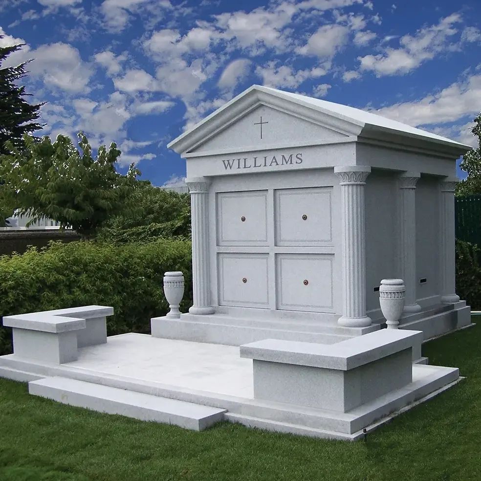 White mausoleum with the name WILLIAMS engraved, set in a green cemetery under a partly cloudy sky