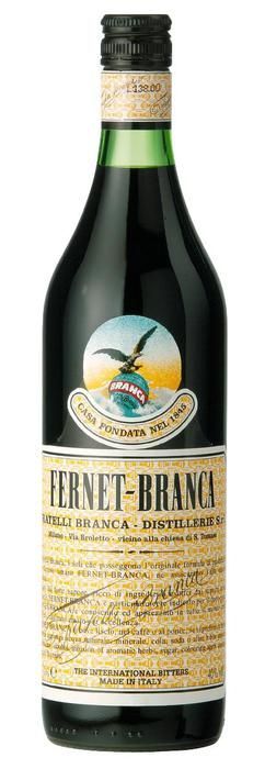 Una botella de Fernet-Branca, de vidrio oscuro, con etiqueta verde y etiqueta amarilla con texto.