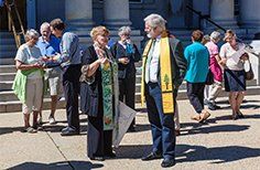 A group of people are standing outside of a church talking to each other.