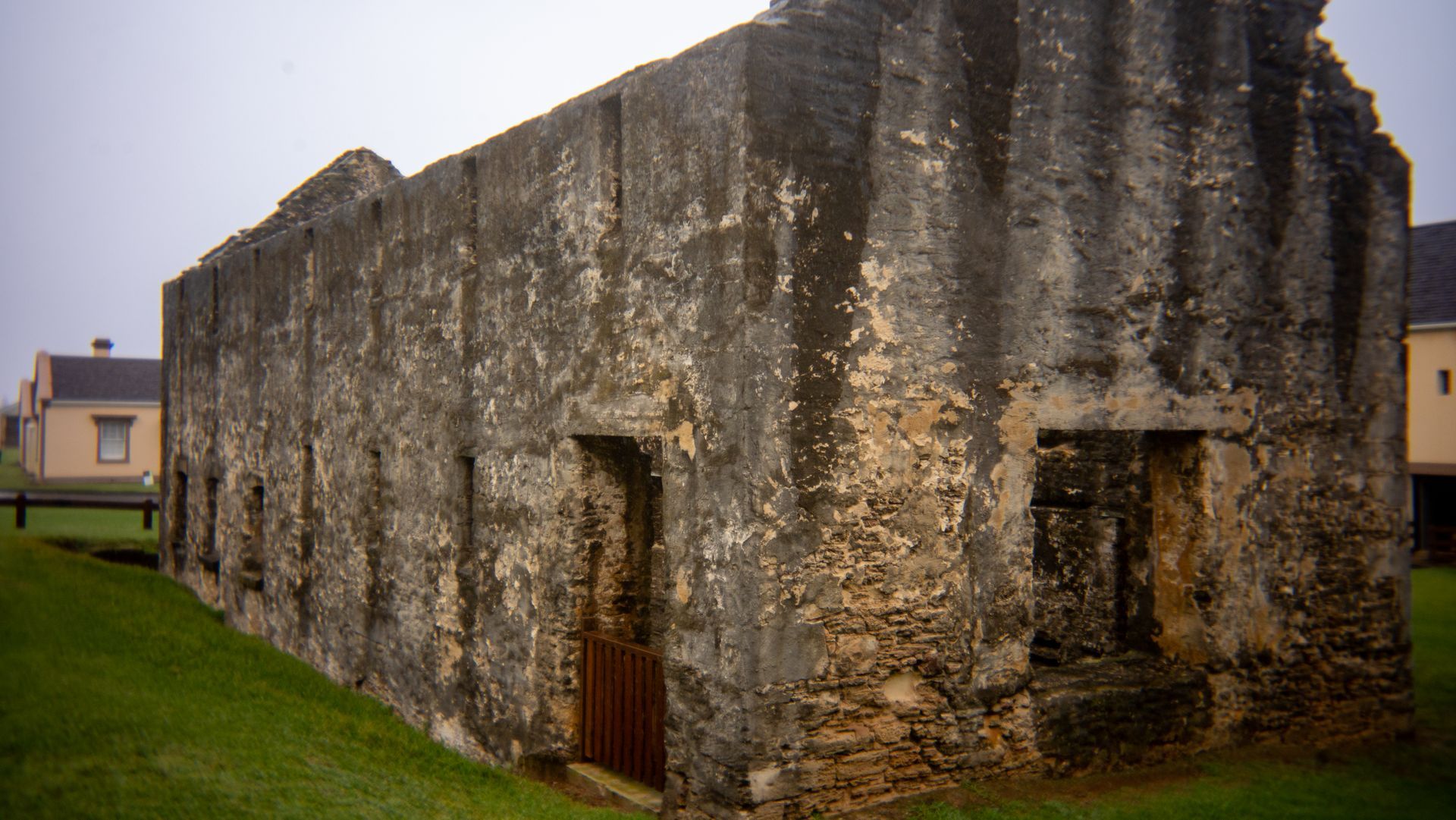 Old stone building with weathered walls and a grassy path beside it
