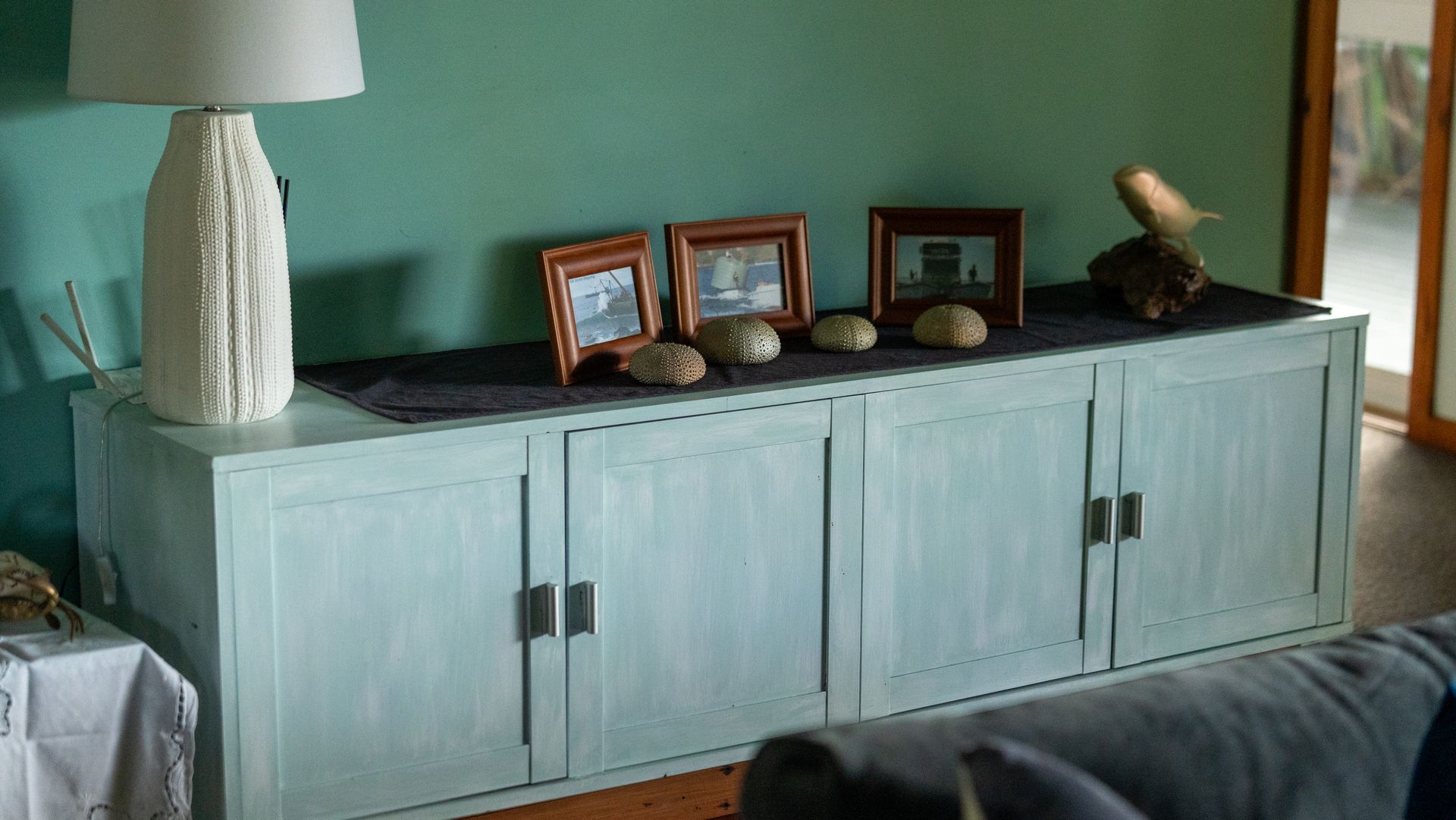 Light blue cabinet with framed photos and decorative objects on top in a living room