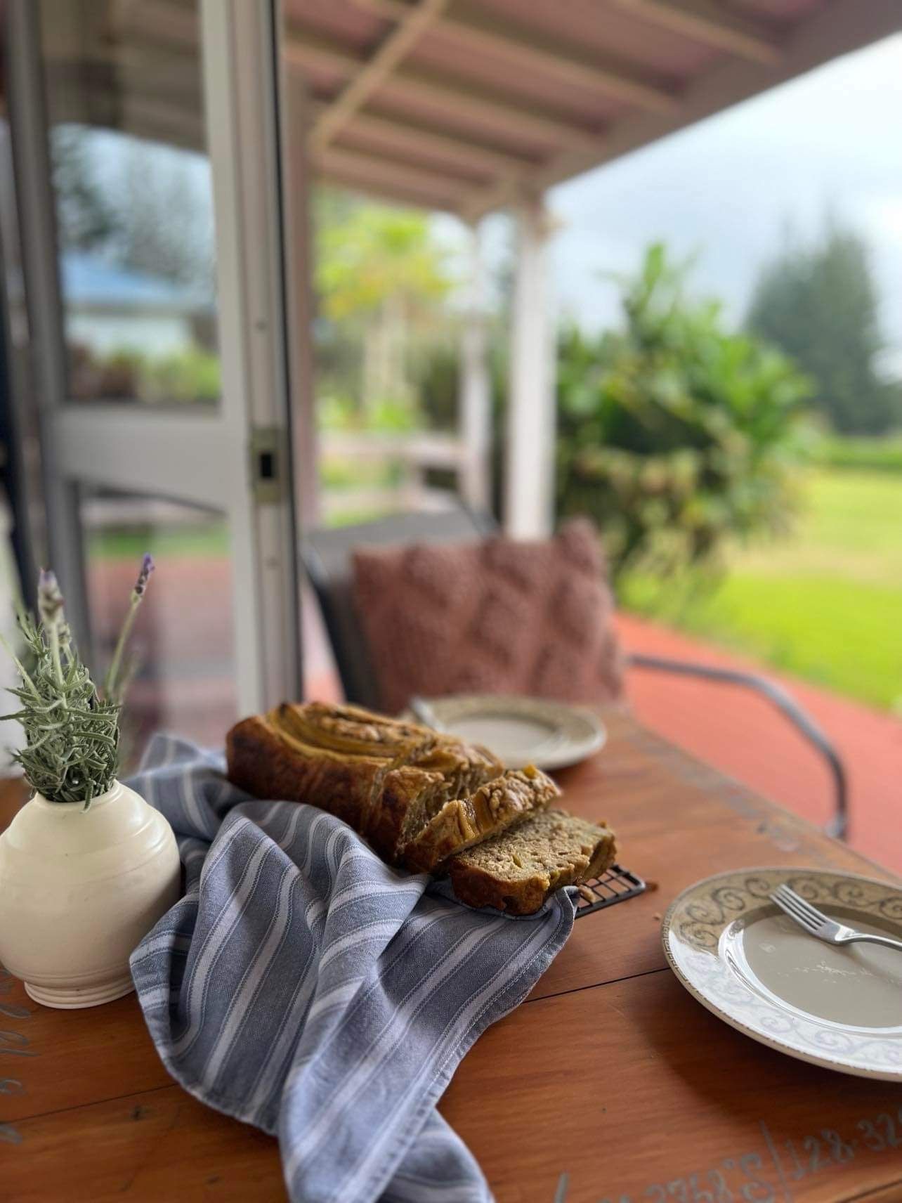 Loaf of sliced bread on a wood table with a vase, a plate and a fork outdoors. Norfolk Island Trade Winds Seniors Sanctuary