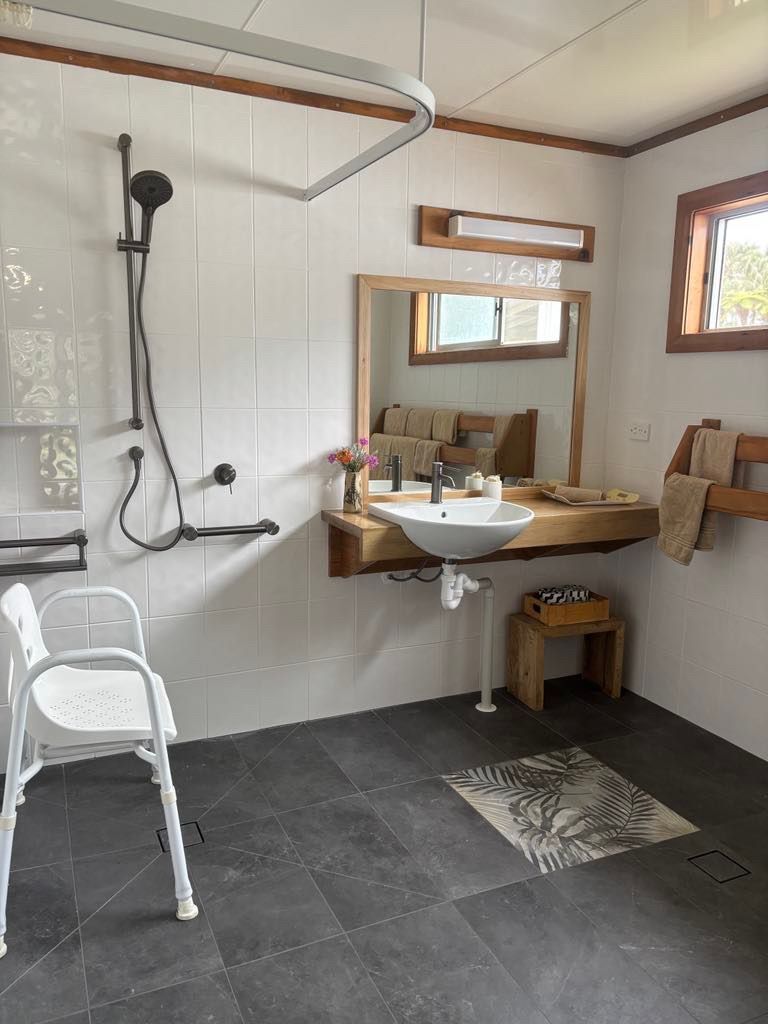Accessible bathroom with a shower seat, sink, and grab bars. Norfolk Island Trade Winds Seniors Sanctuary