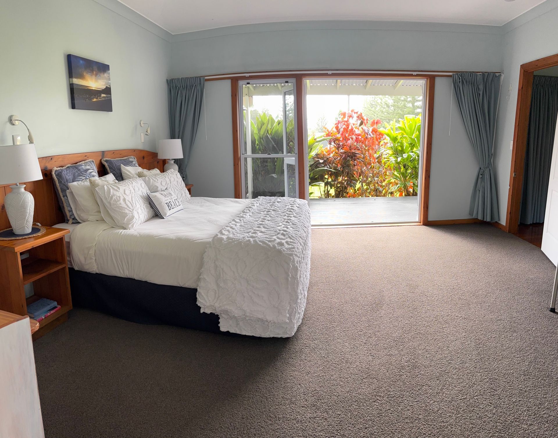 Bedroom with a queen-sized bed, sliding doors to a patio. Norfolk Island Trade Winds Seniors Sanctuary