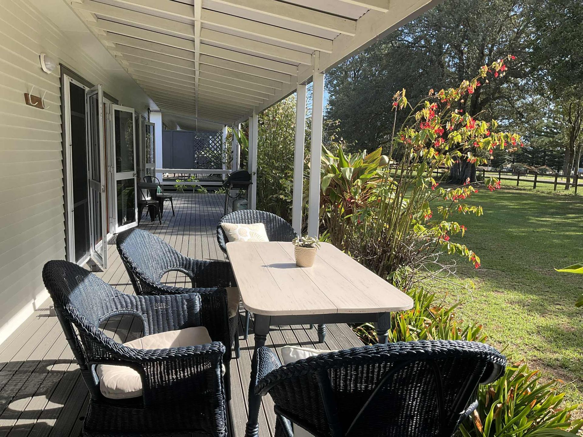 A porch with a table and chairs overlooking a grassy yard with trees. Norfolk Island Trade Winds Seniors Sanctuary