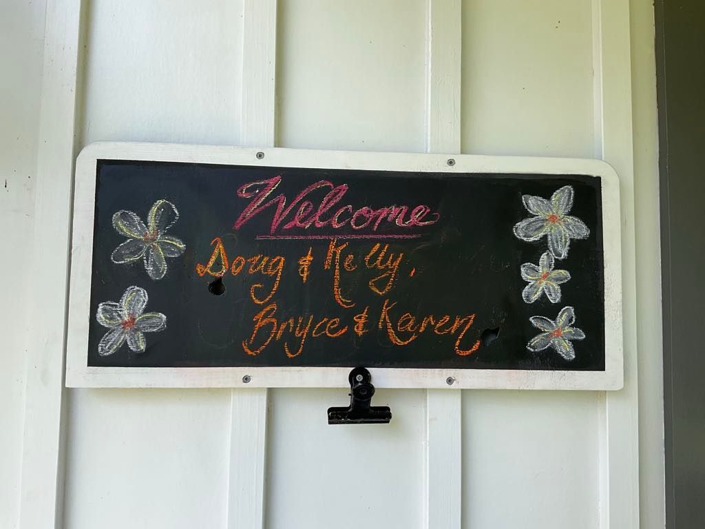 Chalkboard sign welcomes Doug & Kelly and Bryce & Karen, decorated with flowers. Norfolk Island Trade Winds Seniors Sanctuary