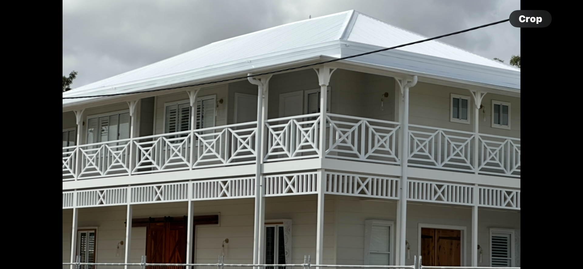 Two-story white building with decorative white railings and a white roof. Cloudy sky in background — Roof Tek CQ in Gracemere, QLD