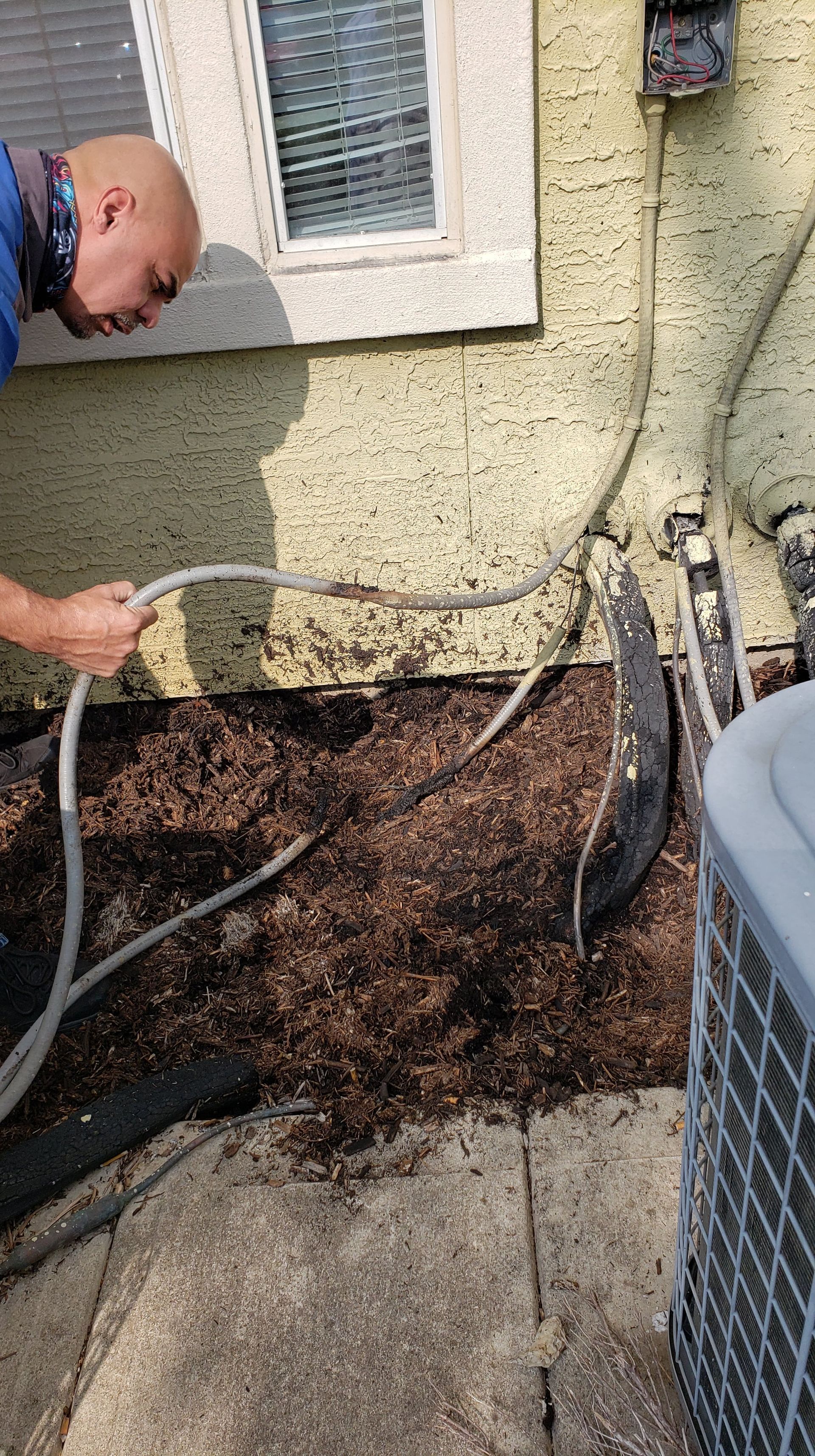 A man is holding a hose in front of a house.