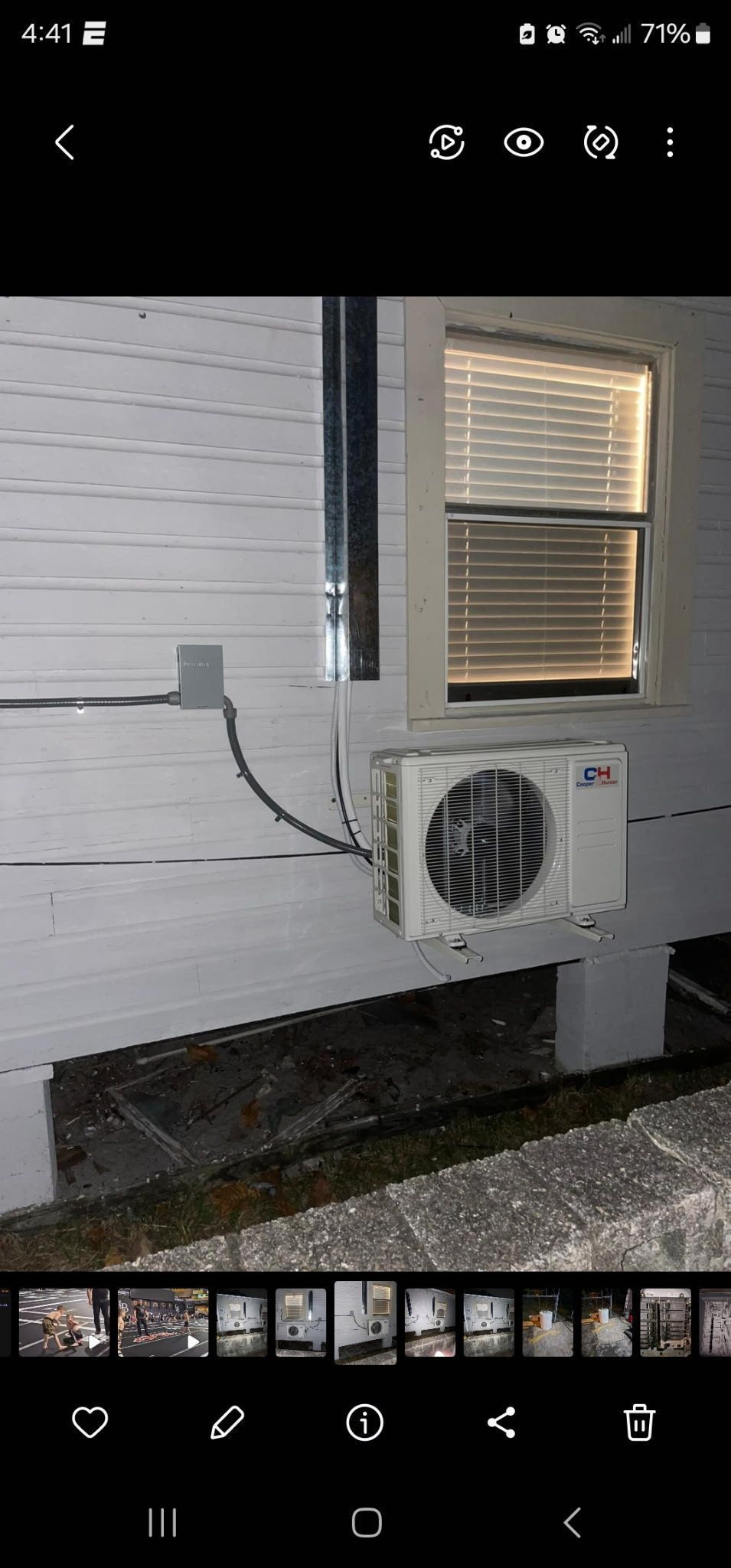 White building with an air conditioning unit below a window with closed blinds.