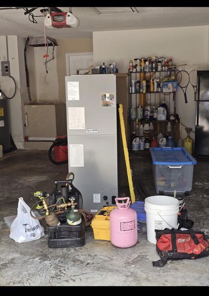 Garage with HVAC equipment, tools, and a new unit, suggesting installation or repair work.