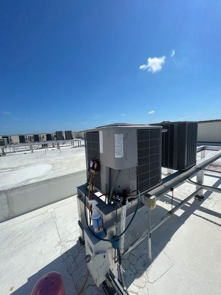 Rooftop HVAC units under a bright blue sky. White flat roof with multiple units.