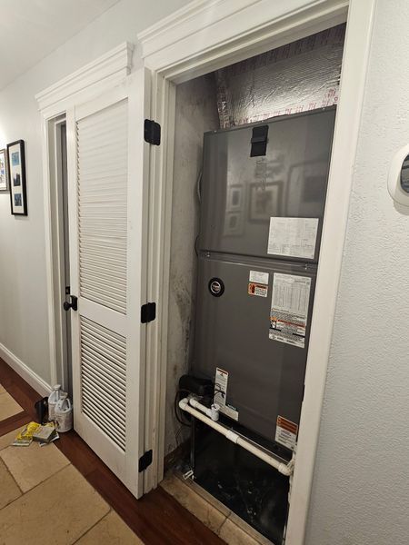 HVAC unit in a closet with a louvered door, hallway setting.