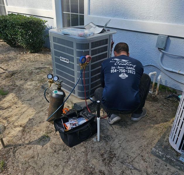 HVAC technician works on AC unit outside a building, using gauges and tools.