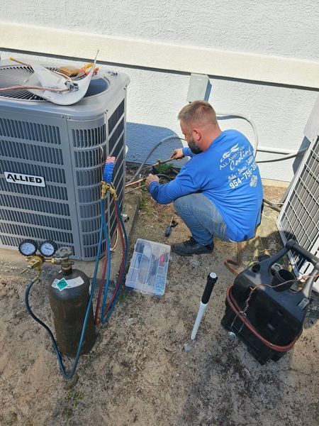 HVAC technician repairing an Allied air conditioning unit outdoors, using tools.
