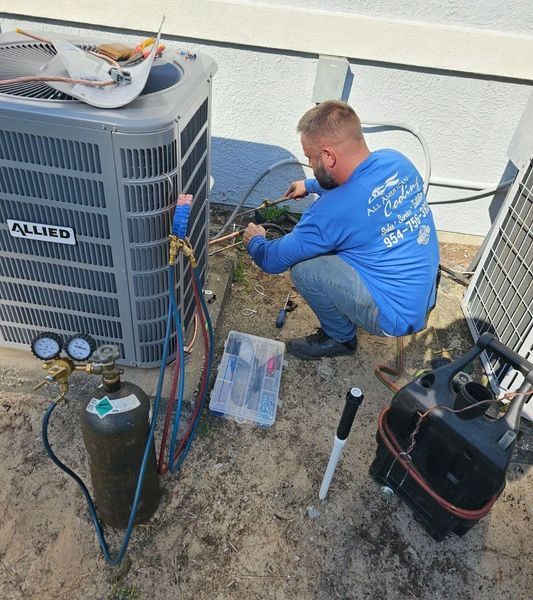 HVAC technician repairing an air conditioning unit outside, using tools and gauges.