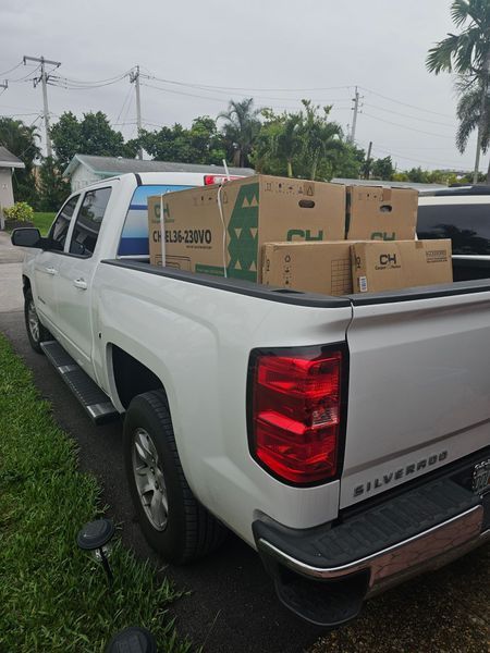 White pickup truck bed filled with cardboard boxes, parked on a residential street.