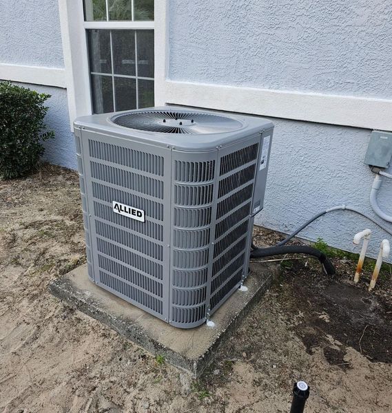 Gray Allied air conditioning unit outside a light blue building next to a window.
