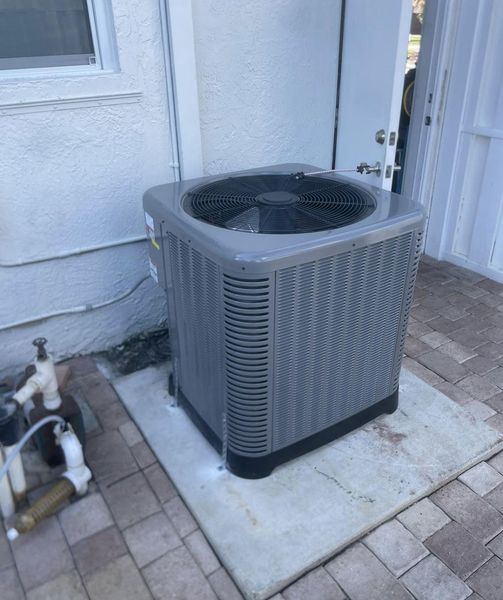 Gray air conditioning unit outside a white building.