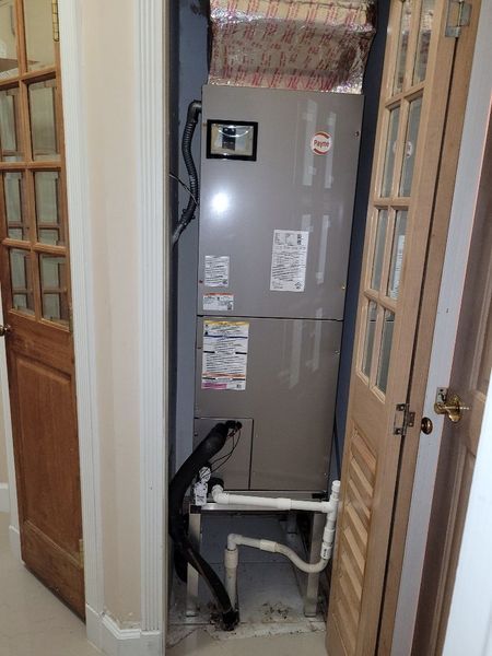 Air conditioning unit inside a closet, pipes visible, flanked by wooden doors.