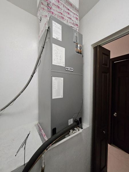 Gray HVAC unit in a utility closet next to a doorway. Ductwork visible.