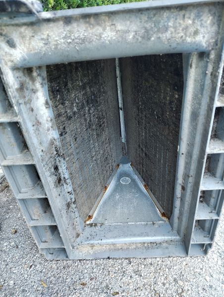 Metal HVAC unit with visible coils and debris. Gray frame, outdoor setting.