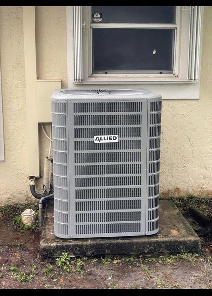 Gray Allied air conditioning unit outside a building, beneath a window.