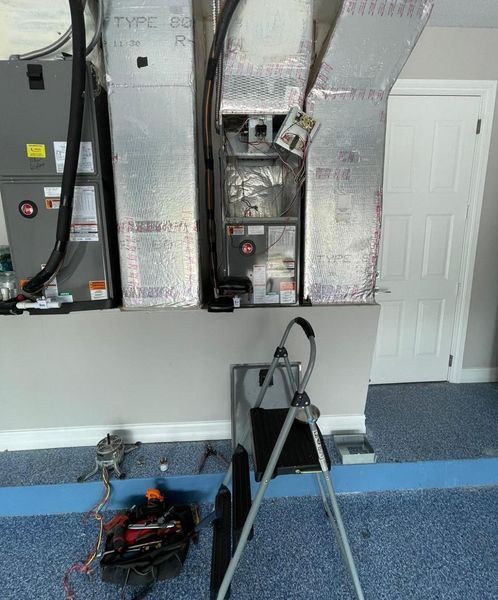 HVAC system in a room with blue flooring. A tripod with equipment is in front of it.