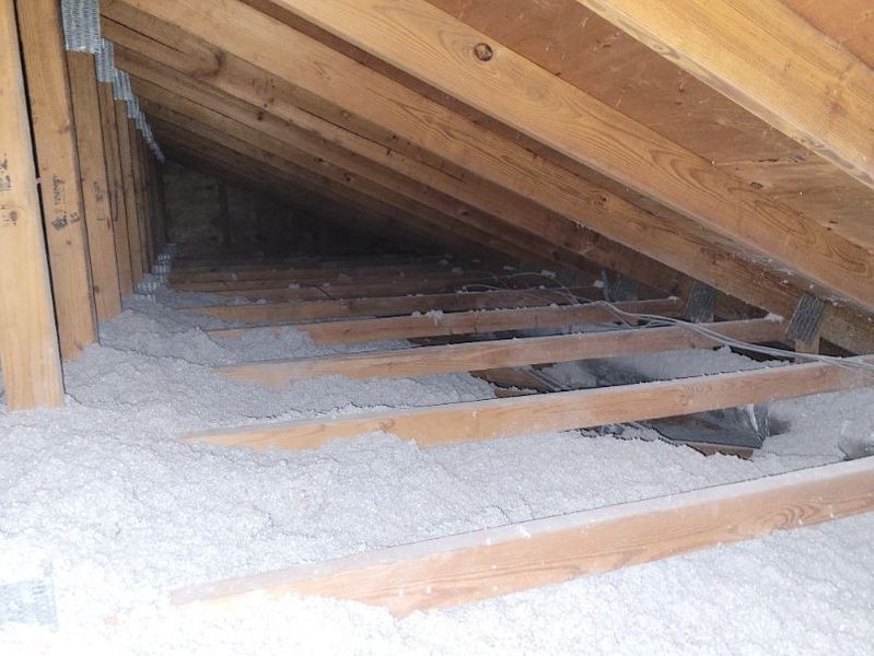 Attic interior with wooden beams and insulation.