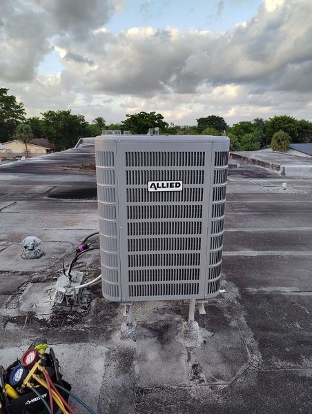 An Allied air conditioner unit on a rooftop. The sky is cloudy, and gauges sit nearby.