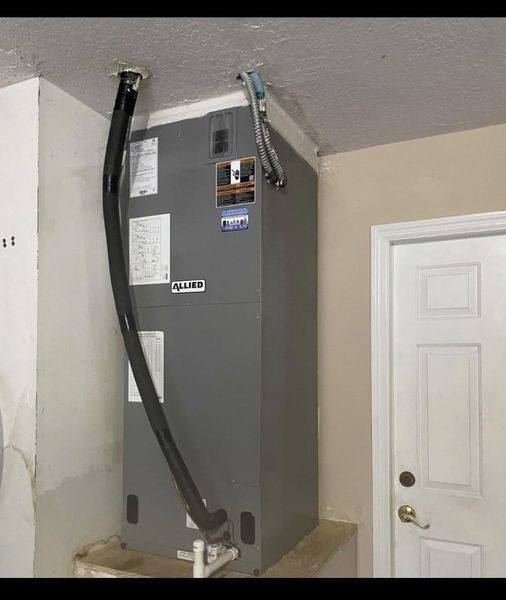 Gray HVAC unit installed near a white door and ceiling. Black tubing extends from the unit.