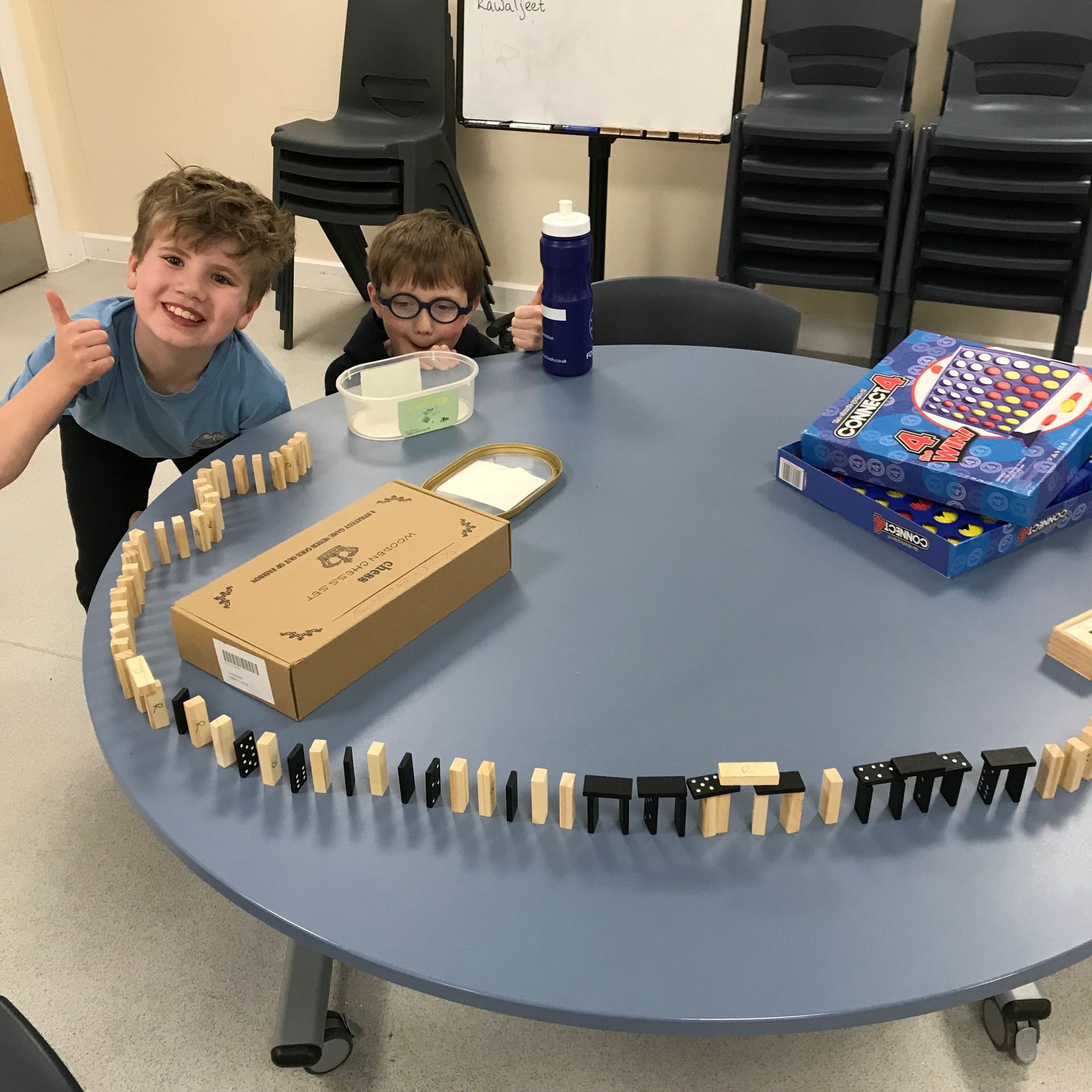 Two young boys are sitting at a table with dominoes on it
