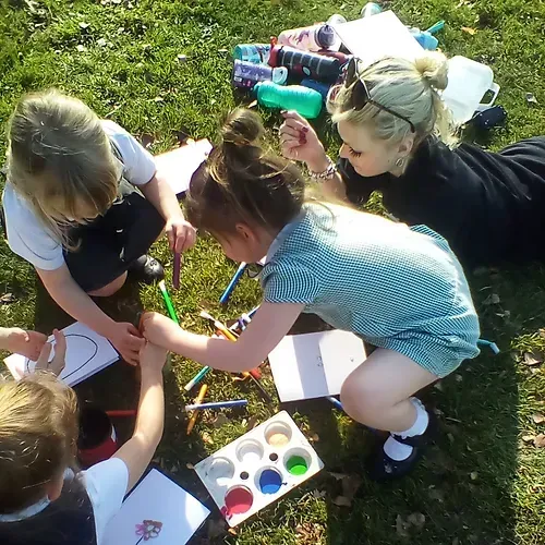 A group of children are laying on the grass painting