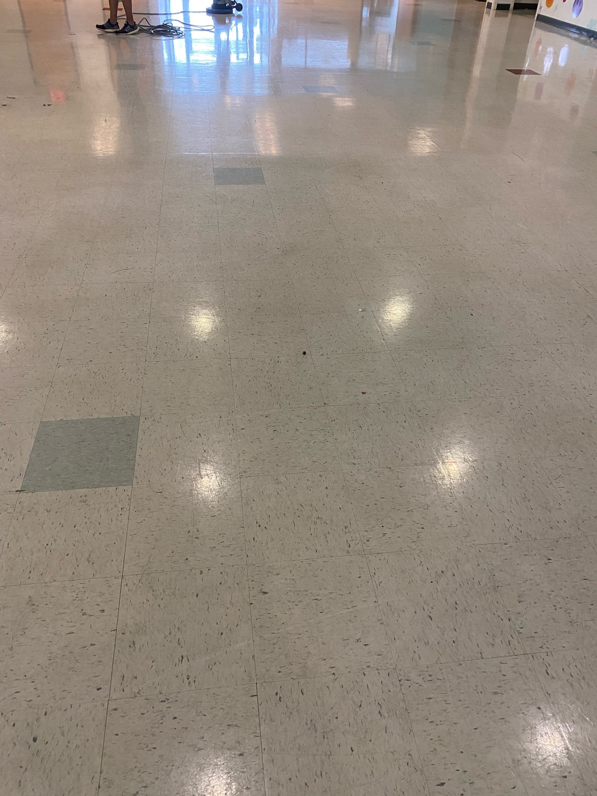 Shiny speckled floor in a bright indoor hallway with light reflections and floor tiles